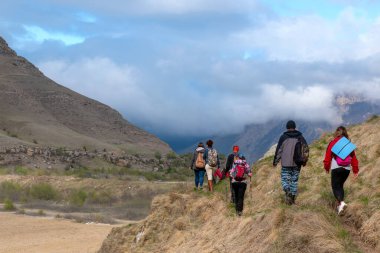 Bylym köyü, Kabardino-Balkarian Cumhuriyeti, Rusya, 03 / 03 / 2019 Dağlarla çevrili bir göl kenarında yürüyen bir grup turist.