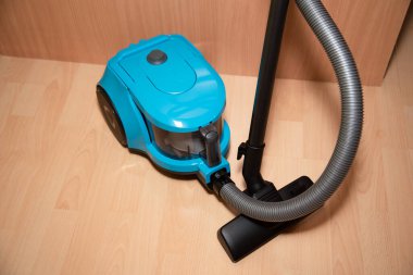 Poşetsiz elektrik süpürgesi bir evin zemininde duruyor.