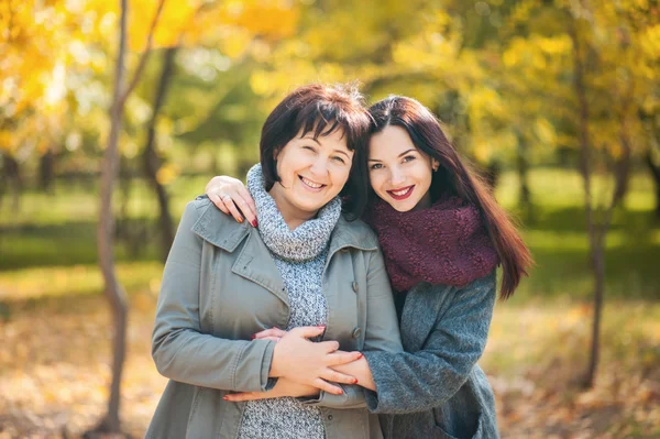 Sarılma ve kamera parkta bakarak yetişkin kızıyla birlikte gülümseyen beyaz kıdemli anne portresi