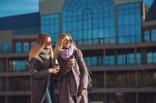 Δύο όμορφες νεαρές γυναίκες, μιλάμε ενώ το περπάτημα στο δρόμο μετά από ψώνια κρατώντας τον καφέ και να χαμογελά. — Φωτογραφία Αρχείου
