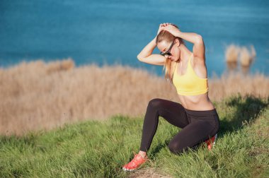 Eğitim sırasında biraz ara. Güzel genç kadın bir süre için rahatlatıcı ve tarak saç egzersizleri önce kuyruk güneşli doğal zemin üzerine oturuyor.