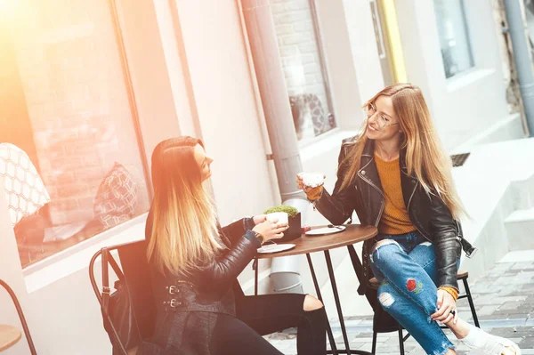 Twee mooie jonge blonde vrouwen drinken koffie en roddelen in mooi restaurant buiten. Het weer is groot en zonnig voor het wandelen door rust ontspannen en tijd doorbrengen met de beste vrienden — Stockfoto