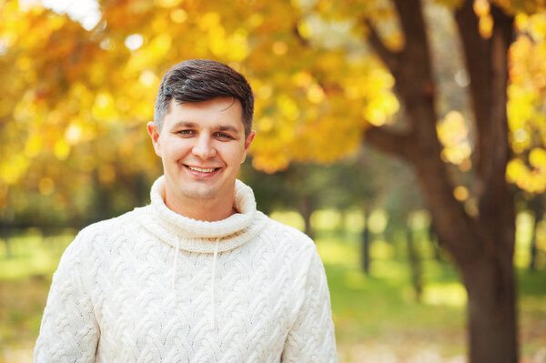 Autumn is coming! Be happy today! Close up portrait of young handsome brunette man staying in autumn park smiling and looking in cam. Emotions, people, season, fashion concepts