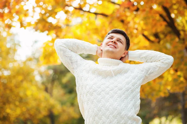 Mutlu genç Kafkas yakışıklı adam sonbahar parkta kalmak, germe ve kafa dokunmadan. Tembel sonbahar gün. Adam boş zamanlarında açık rahatlatıcı. İş, çalışma, insanlar kavramları