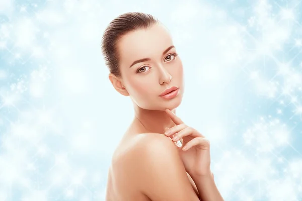 Güzel genç kız mavi arka plan ve kar yüzünde çok dokunaklı. Plastik cerrahi, facelift ve gençleştirme kavramı.