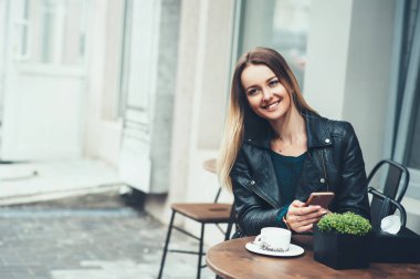 Kafe kaygısız zamanında. Çekici genç kadın arkadaşına kafe açık ve yazma hızlı mesaj oturan bir gülümseme ile.