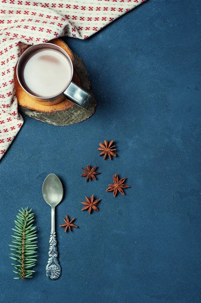 Frame of Cup of Cacao Coffee Beans Cinnamon sticks Spoon and Fir Branch on Dark Texture Table decorated Napkin. Kitchen Ingredients Winter or Autumn Composition. Flat lay Top view Copy Space Vertical.