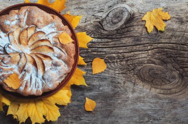Taze pasta elmalı turta charlotte ahşap masa zemin üzerine sarı sonbahar yaprakları ile süslenmiş. Sonbahar gıda yemek mutfağı ev yapımı rustik kavramları. Tatil yemek kopya alanı Flatlay