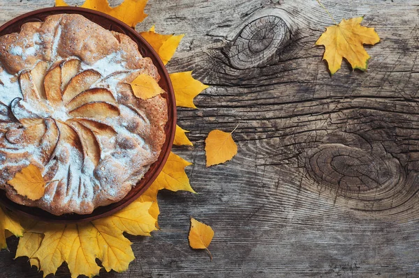 Taze pasta elmalı turta charlotte ahşap masa zemin üzerine sarı sonbahar yaprakları ile süslenmiş. Sonbahar gıda yemek mutfağı ev yapımı rustik kavramları. Tatil yemek kopya alanı Flatlay