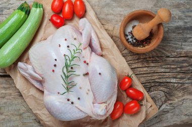 Biberiye domates tuz biber ve kabak ahşap gemide aşçı için hazır çiğ tavuk eti. Rustik arka plan. Gıda mutfak mutfağı sağlık kavramı. Diyet yemek