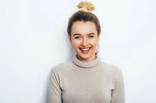 Yatay portre çekici gülümseme ile neşeli kadının saç topuz beyaz arka plan üzerinde izole kazak giyiyor olması. Onun hoş duygular gösterilen güzel kadın. İnsanlar güzellik moda