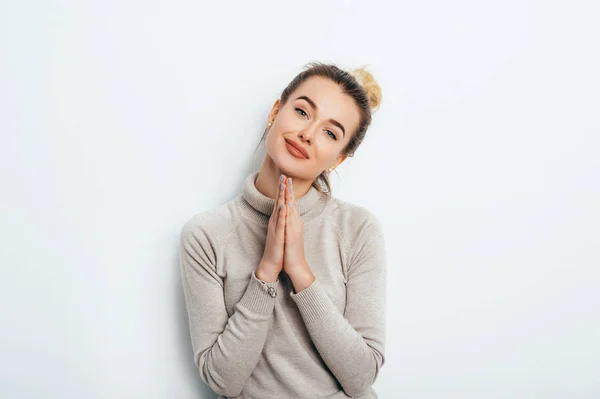 Retrato horizontal de la mujer bonita mantiene la palma juntos, tiene expresión complacida, rogando le pide al novio que compre algo. La mujer atractiva alegre hace la petición, ruega por la misericordia. Esperanzado joven adulto — Foto de Stock