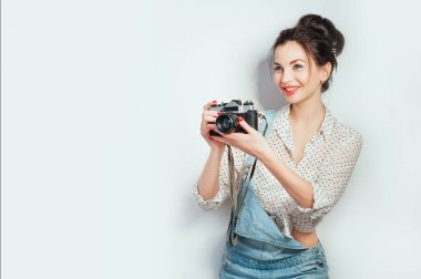 Moda bak, güzel genç kadın model beyaz duvar poz denim giysileri giyen retro film kamera ile. Anlamlı güzellik kız fotoğrafçı PhotoCam tutarak. Duygular yaşam tarzı kavramları