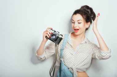 Moda bak, güzel genç kadın modeli ile retro fotoğraf makinesi beyaz duvara poz denim giysiler giyiyor. Anlamlı güzellik kız fotoğrafçı PhotoCam tutarak. Duygular yaşam tarzı kavramları