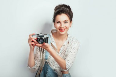 Moda bak, güzel genç kadın modeli ile retro fotoğraf makinesi beyaz duvara poz denim giysiler giyiyor. Anlamlı güzellik kız fotoğrafçı PhotoCam tutarak. Duygular yaşam tarzı kavramları