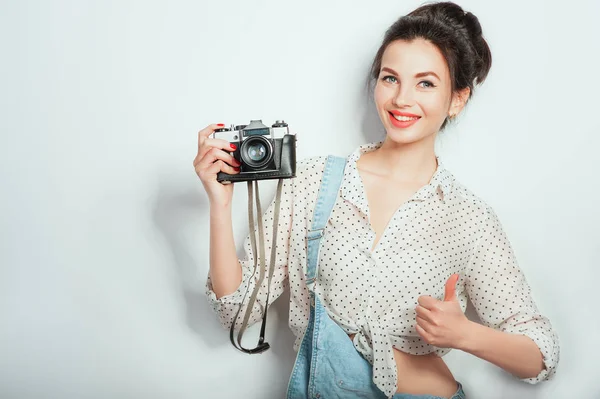 Cool! Pretty cool young woman model with retro camera wearing in denim clothes posing on white wall. Expressive beauty girl photographer holding photocam. Emotions Lifestyle People concepts