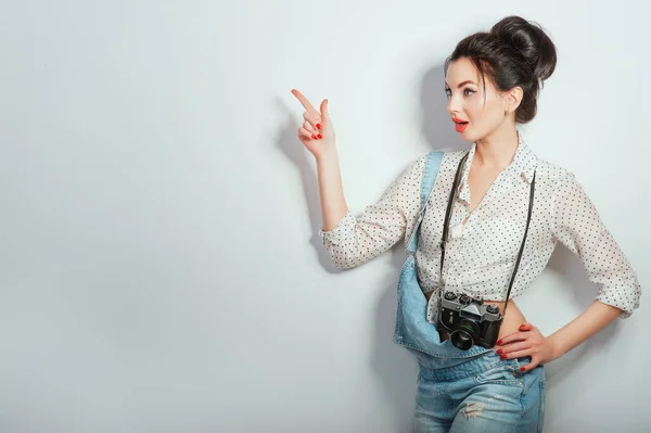 Fashion look, pretty cool young woman model with retro camera wearing in denim clothes pointing on copy space. Expressive beauty girl photographer holding photocam. Emotions Lifestyle People concepts