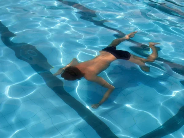 Jeune homme nageant dans la piscine. Vue de dos . — Photo