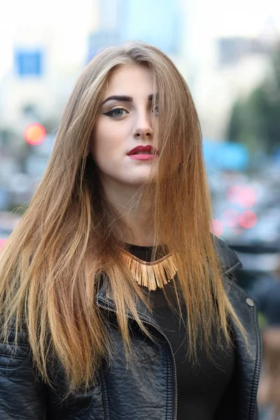 Stylish long-haired woman on a blurred background of city