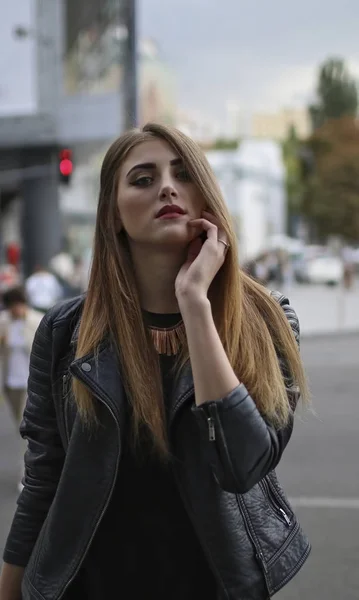 Menina em jaqueta de couro posando no fundo da rua borrada — Fotografia de Stock
