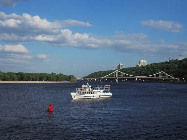 Белая прогулочная лодка с пассажирами на борту отплыла по центру реки в Киеве — стоковое фото