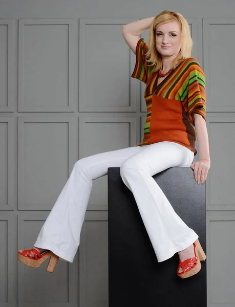 Vacker flicka poserar i studio nära små chear i 1970-talet kläder. — Stockfoto