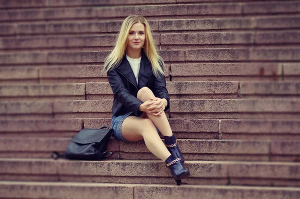 Красива дівчина в чорній куртці сидить на сходах . — стокове фото