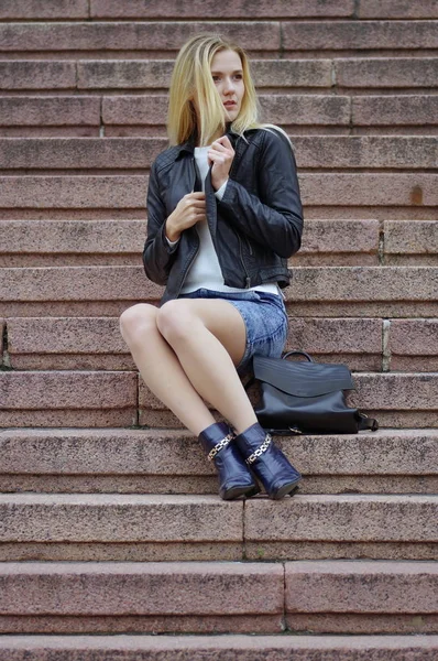 Una bella ragazza con una giacca nera è seduta sulle scale — Foto Stock