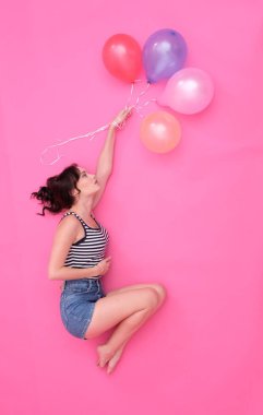 Düşünceli kız renkli balonlarla uçar.