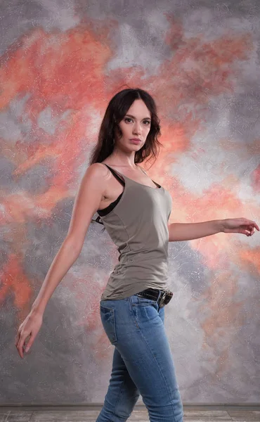 Uma mulher a andar no estúdio. Belas mãos. Ela usa t-shirt e jeans. . — Fotografia de Stock