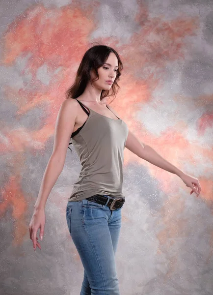 Woman walking at studio shot. Nice hands. She wears t-shirt and jeans. — Free Stock Photo