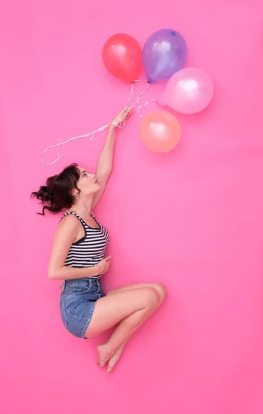 Thoughtful girl flies with colored balloons. Royalty Free Stock Images