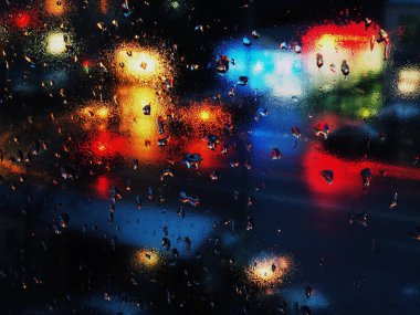 Gece trafik ışıkları penceresindeki soyut yağmur damlaları.