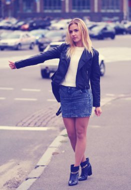 Sarışın güzel görünümlü bir kadın yolda bir araba almak çalışır.