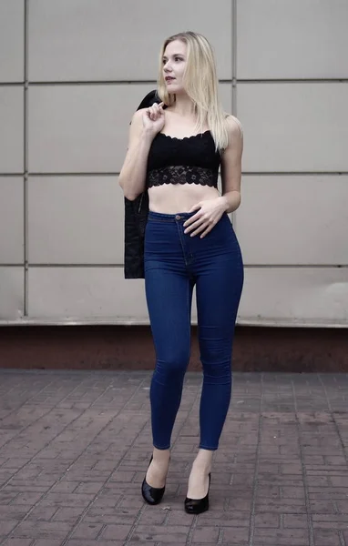 Menina bonita posando em jeans azuis e top de cultura preta . — Fotografia de Stock