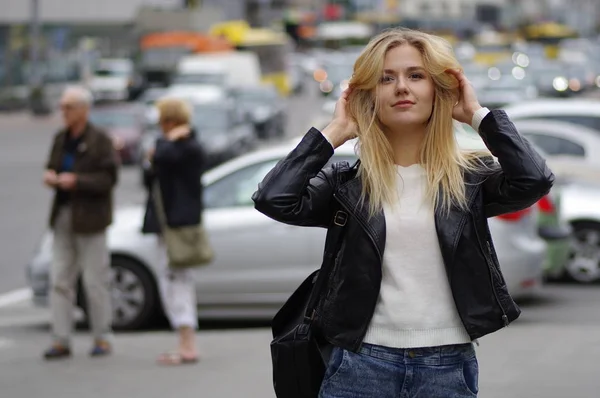 Nice girl poses on a street raising her hair with hands.
