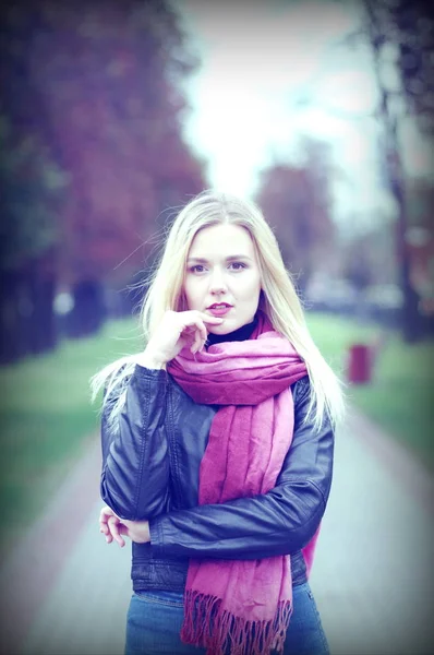 Krásná mladá dívka s zamyšlenýma očima v kožené bundě, modré džíny a purpurové šátek — Stock fotografie