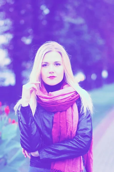 Thoughtful pretty young woman in leather jacket, blue jeans and red scarf — Stock Photo, Image