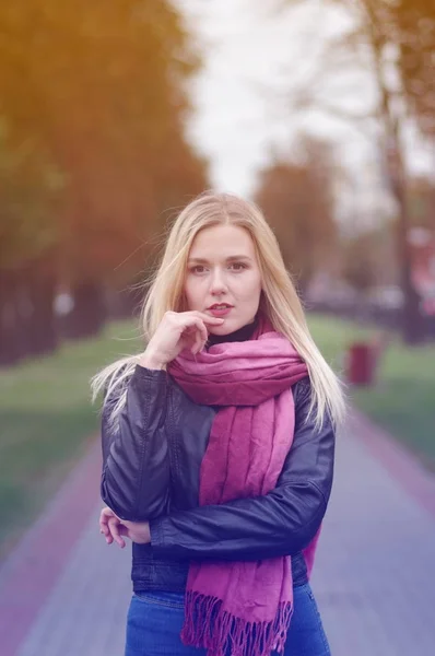 Krásná mladá dívka s zamyšlenýma očima v kožené bundě, modré džíny a červeným šátkem — Stock fotografie