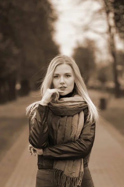 Bella ragazza con gli occhi rimuginanti in giacca di pelle, jeans e sciarpa — Foto Stock