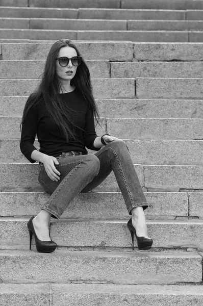 Ritratto urbano di una bruna in jeans e una T-shirt nera con maniche lunghe. Street fashion . — Foto Stock