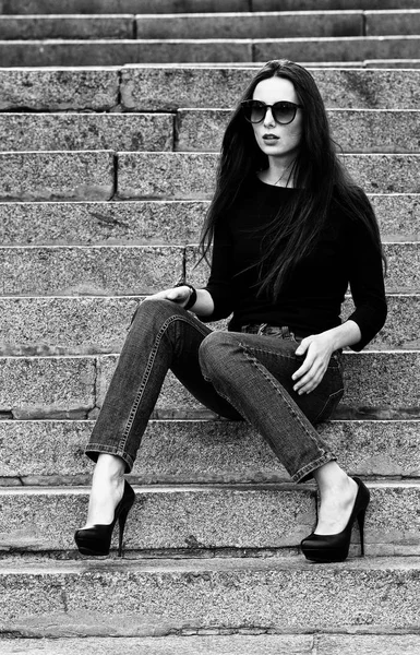 Retrato urbano de uma morena em jeans e uma camiseta preta com mangas compridas. Moda de rua . — Fotografia de Stock