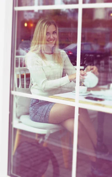 La chica sonríe en un restaurante con una tetera. Con buen humor . — Foto de Stock