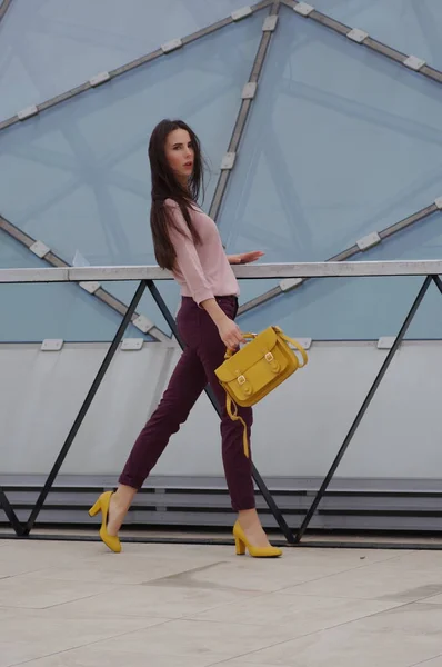 Bella giovane modella in posa in jeans e camicia con borsetta gialla . — Foto Stock