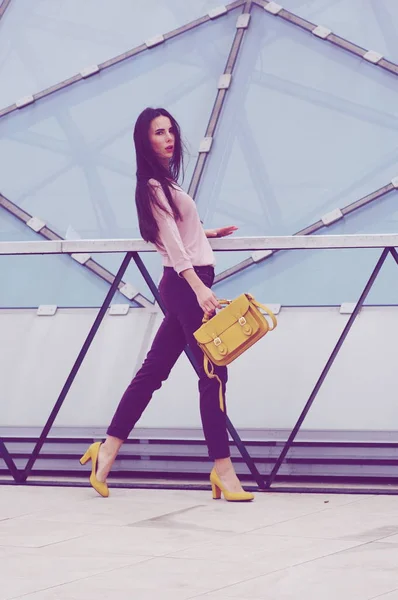 Bella giovane modella in posa in jeans e camicia con borsetta gialla . — Foto Stock