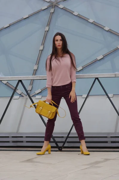 Schönes Mädchen steht in Jeans und Hemd mit gelber Handtasche. — Stockfoto