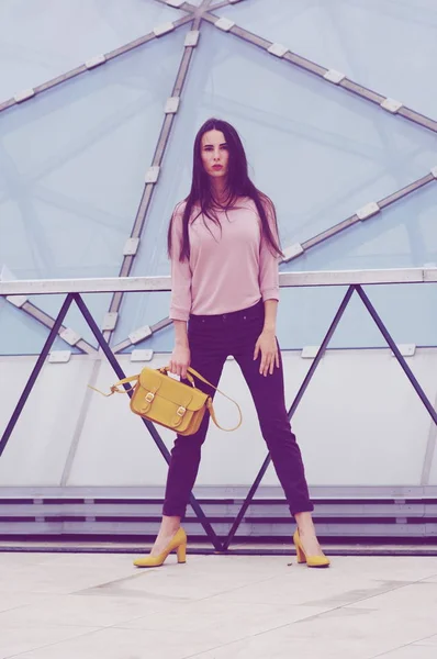 Bella ragazza è in piedi in jeans e camicia con borsa gialla . — Foto Stock