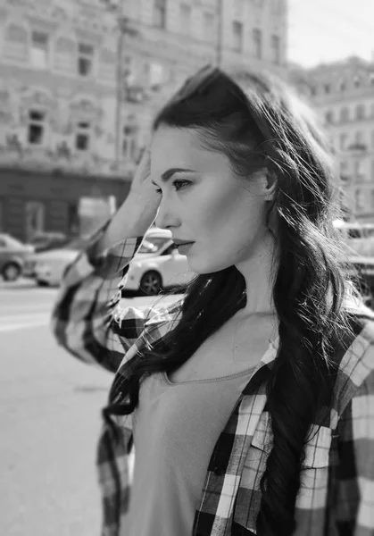 Retrato de uma bela mulher morena em uma camisa xadrez. Estilo urbano de roupas. Óculos de sol na cabeça. Reflexão do céu em copos copos . — Fotografia de Stock