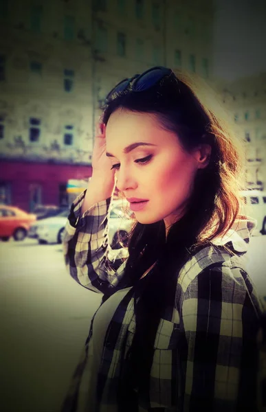 Portrait d'une belle femme brune en chemise à carreaux. Style urbain de vêtements. Lunettes de soleil sur la tête. Reflet du ciel dans les lunettes . — Photo