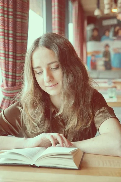 Гарненька студентка читає книгу в кафе — стокове фото